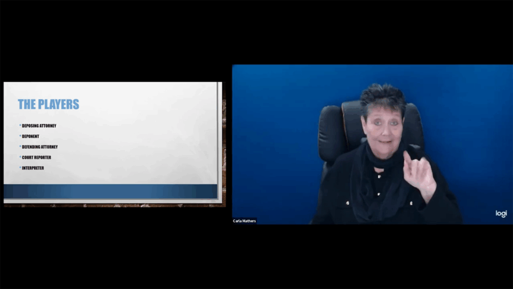 A title slide reads "THE PLAYERS" followed by a bulleted list: "DEPOSING ATTORNEY," "DEPONENT," "DEFENDING ATTORNEY," "COURT REPORTER," and "INTERPRETER." A woman with short dark hair, wearing a black top and scarf, is signing from a black office chair.