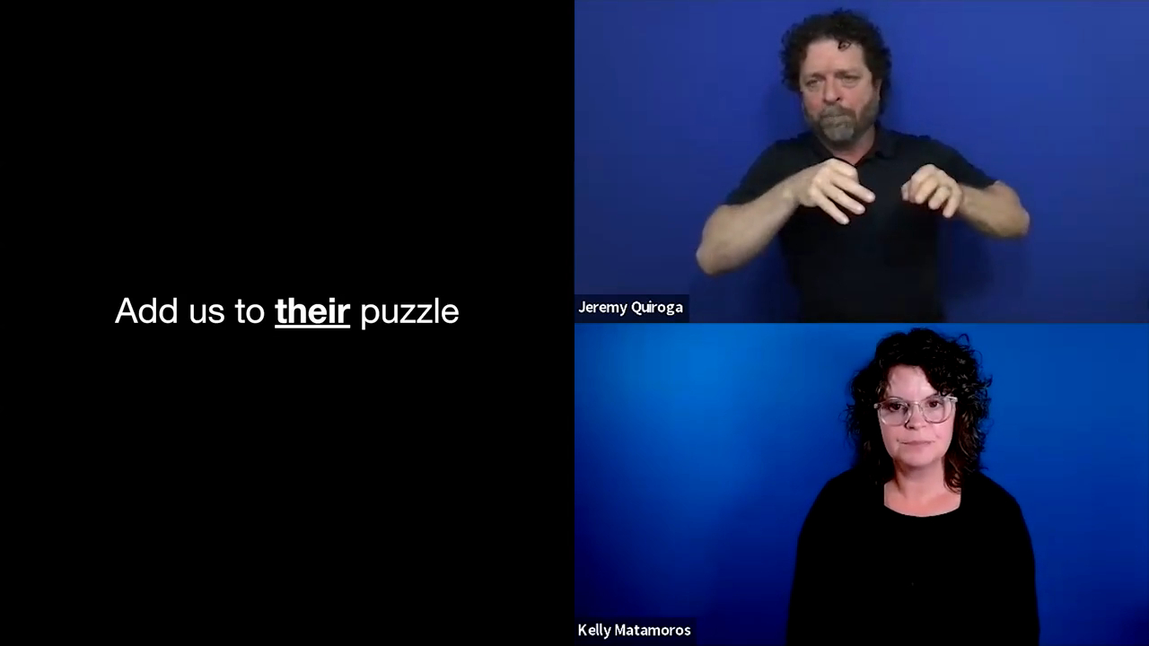 This screenshot displays a split-screen presentation layout featuring text on the left and two stacked video feeds on the right against a solid blue background. The left half consists of a black slide with white text that reads, "Add us to their puzzle," where the word "their" is prominently bolded and underlined. The right half is split vertically into two individual video panels. In the top panel, Jeremy Quiroga, a man with curly dark hair and a beard wearing a black shirt, is actively presenting using sign language, with his name displayed in a small black box in the lower-left corner of his feed. In the bottom panel, Kelly Matamoros, a woman with dark curly hair and glasses wearing a black shirt, looks directly forward, with her name similarly labeled in a small black box in the lower-left corner.